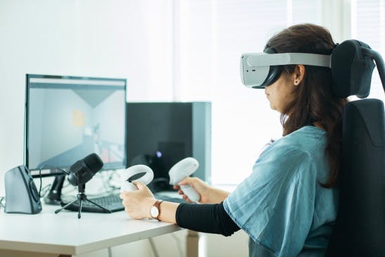 Person working in front of a computer with VR headset on